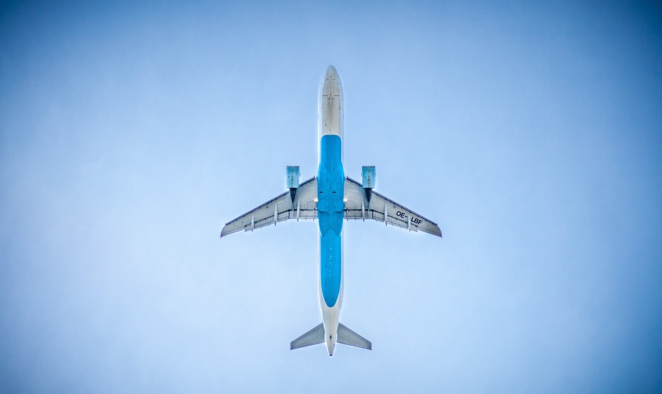 a white and blue plane flies in a clear sky