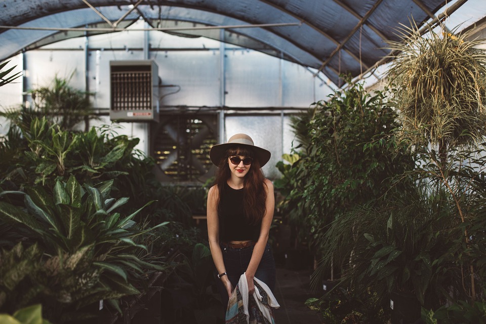 Girl standing inside of a greenhouse surrounded by plants