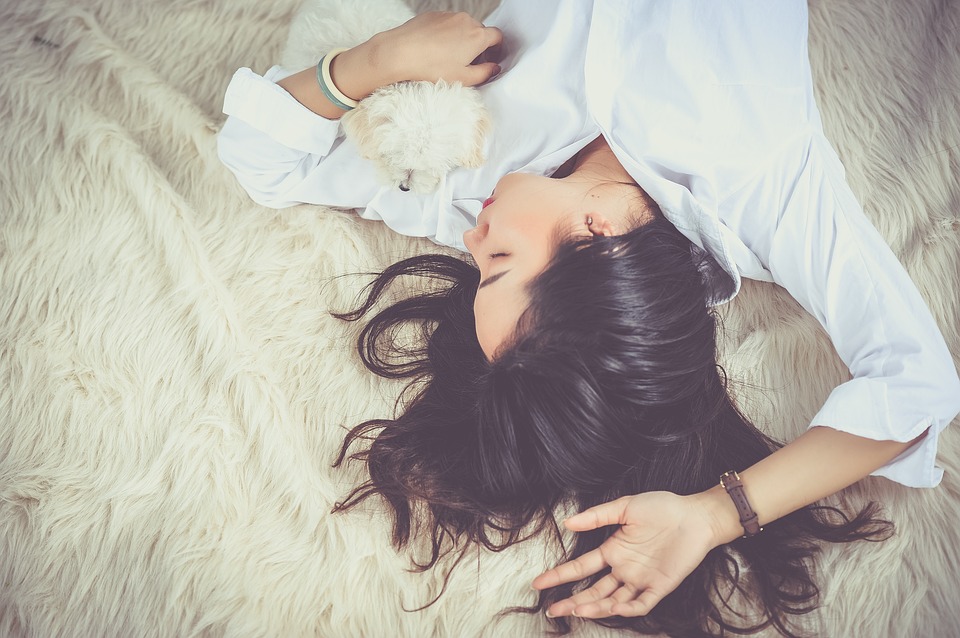 woman sleeping with a puppy in her arms