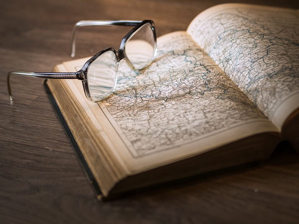 glasses over an old book of opened at a page with a map