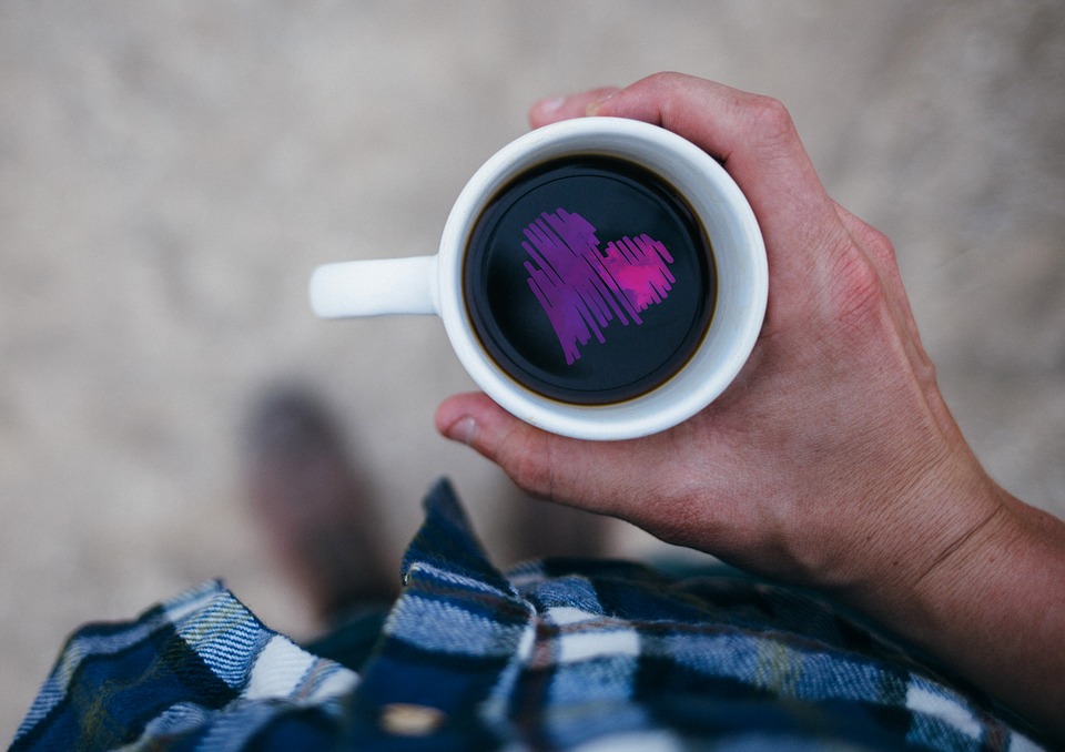 man holding a cup of coffee with a purple heart in the middle of it