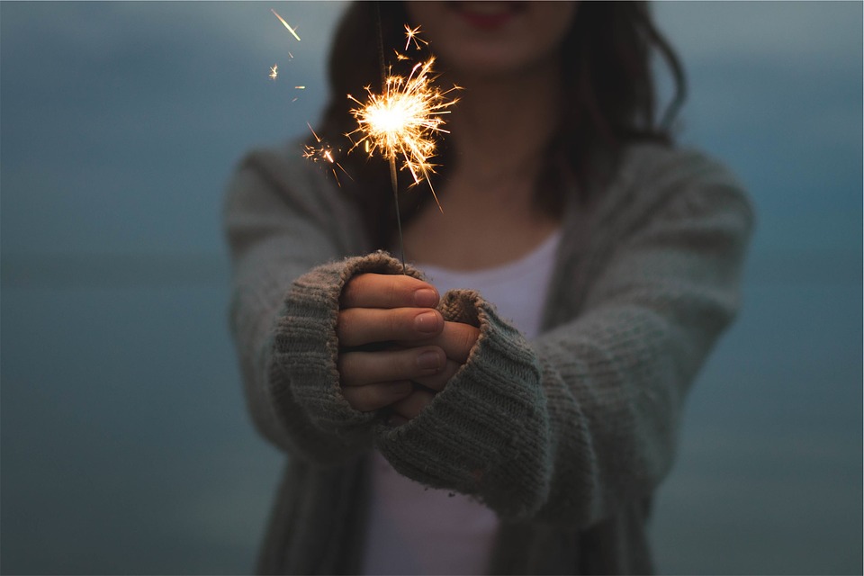 a lady is holding a sparkler in front of her in the centre of a dark blue background