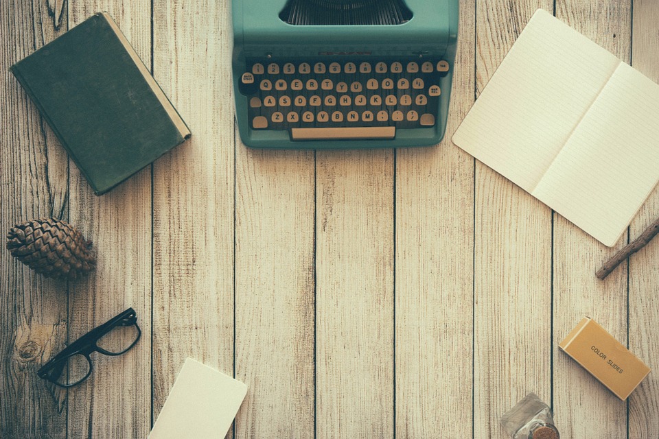 wooden desk with typewriter, stationary and pinecone on top