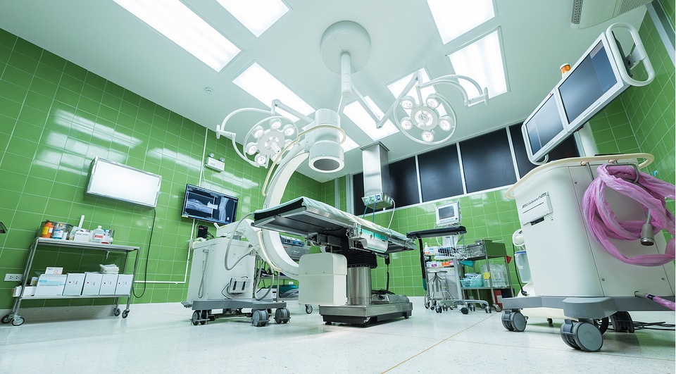 A well lit operating table in a clean hospital surrounded by medical equipment