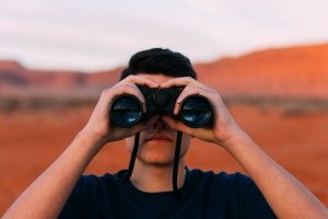 A man hold binoculars up to look at something far away