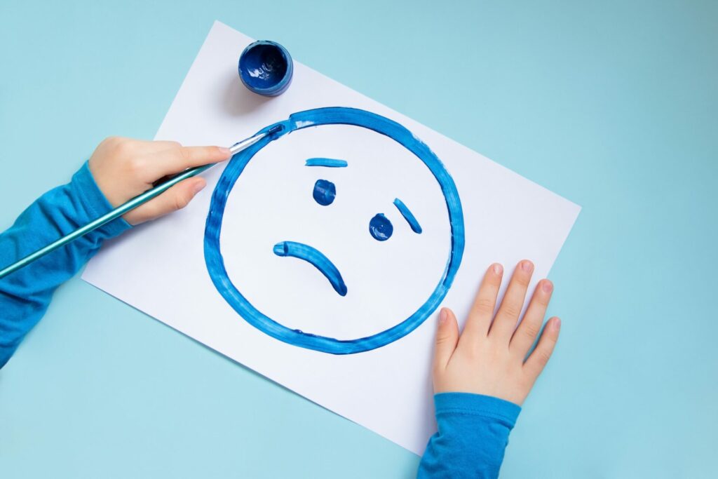 child drawing a sad face in blue - Blue Monday